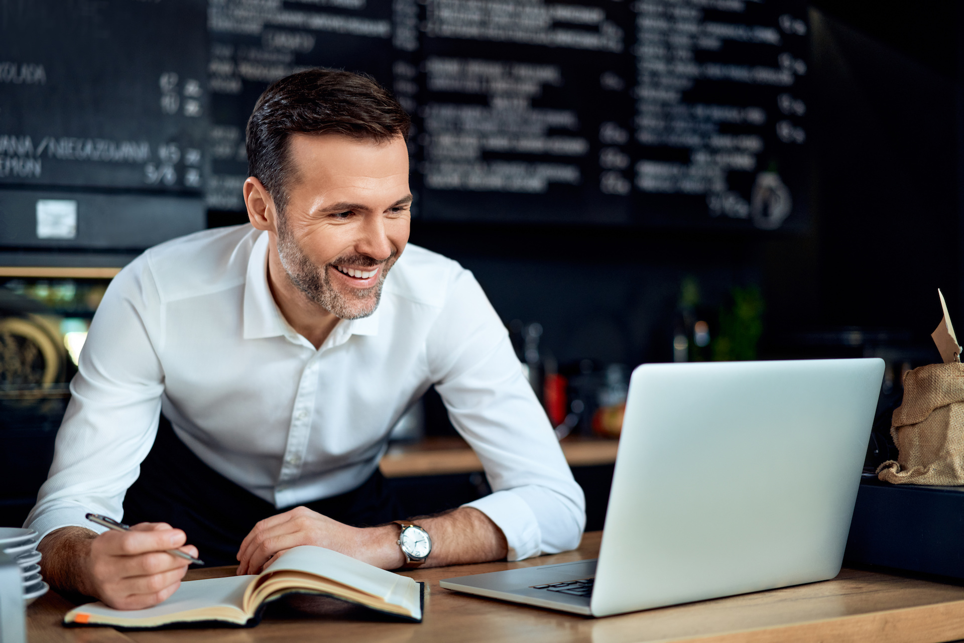 restaurant owner using laptop writing expenses