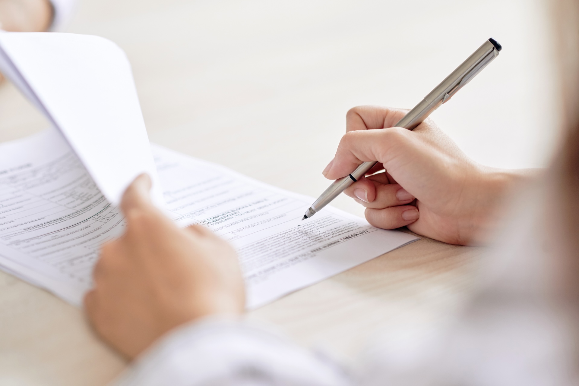 person with pen signing contract at desk