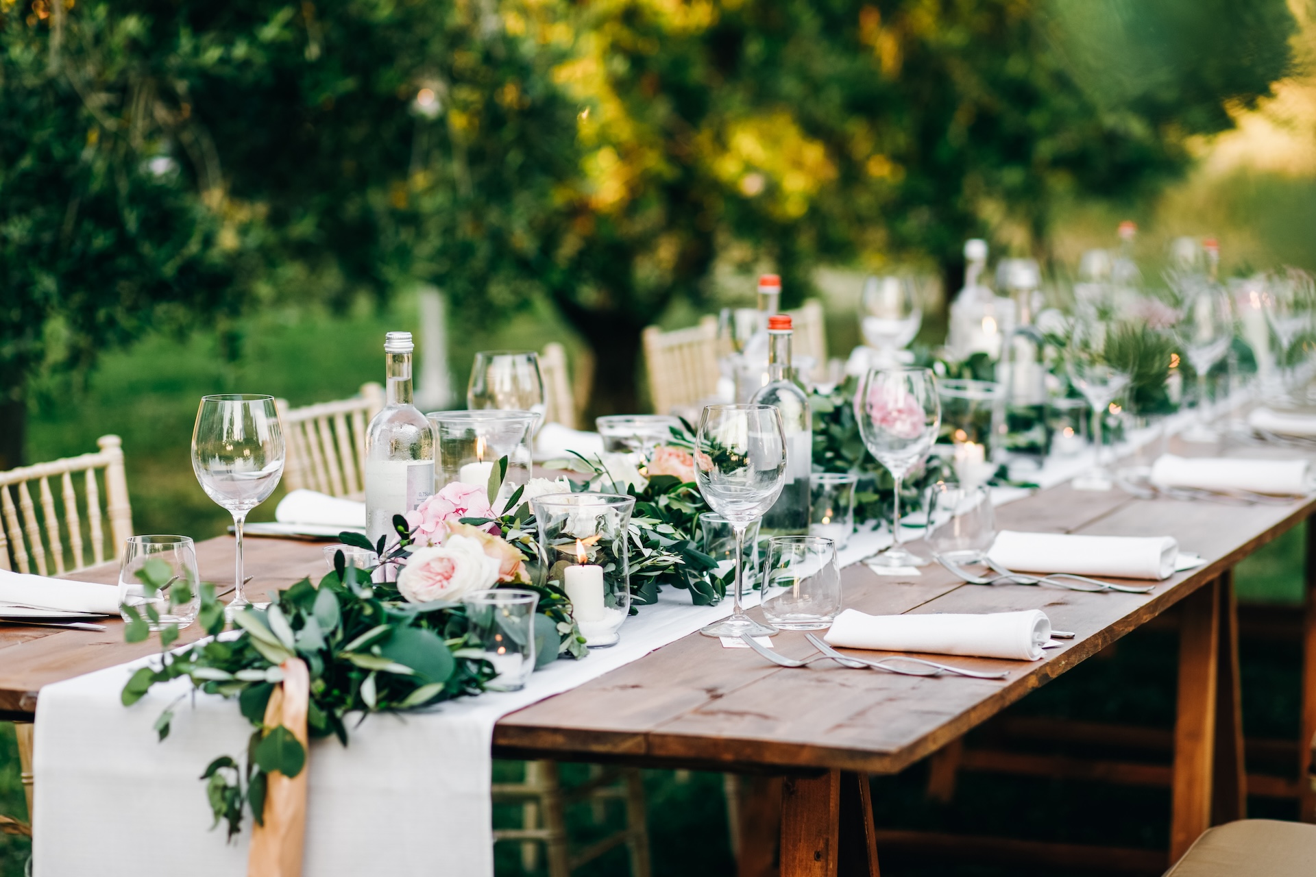 Floral garland of eucalyptus and pink flowers lies on the table for wedding reception