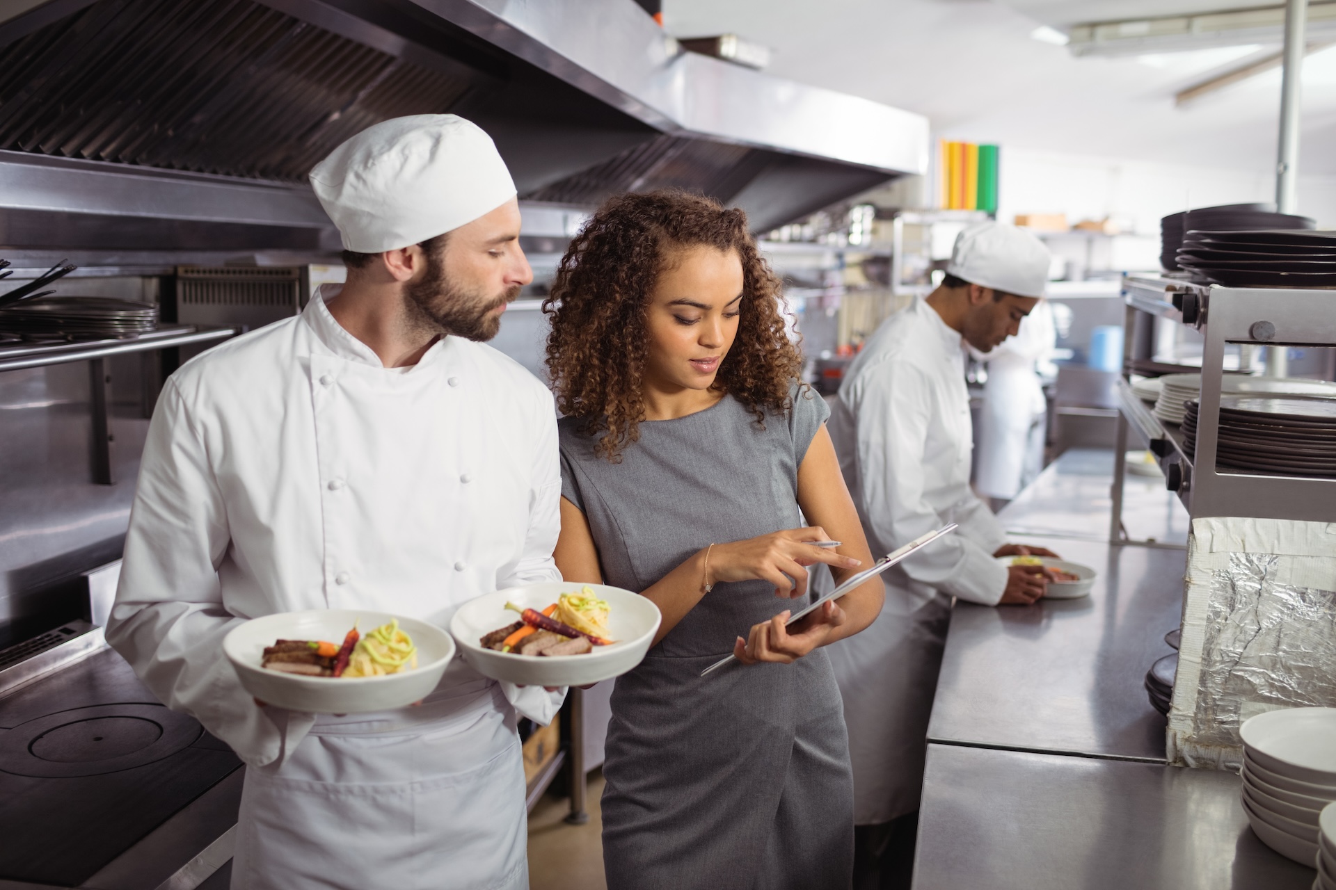 Manager discussing menu on clipboard with chef