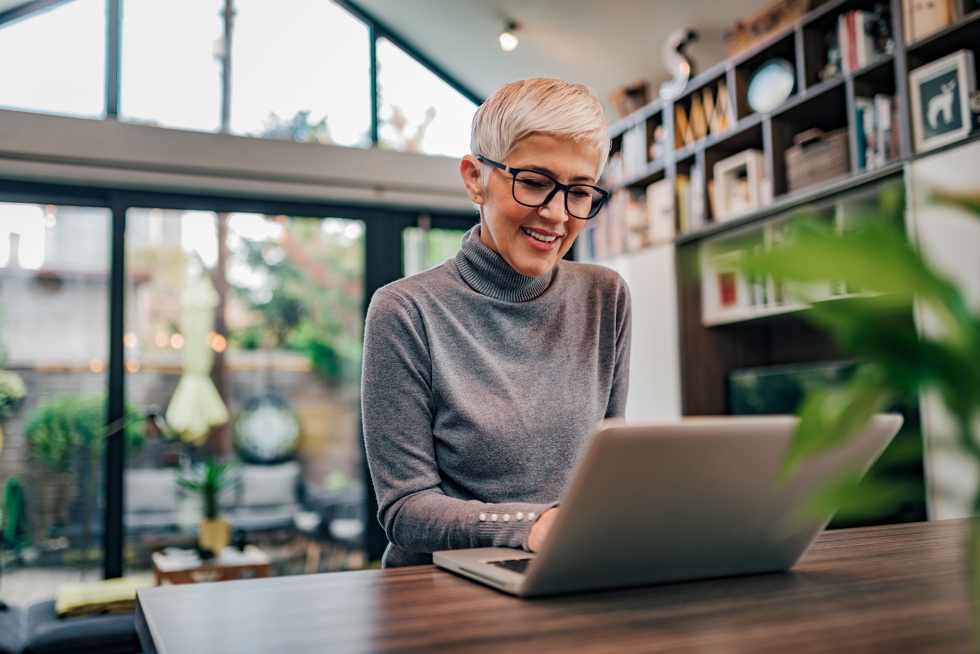 cheerful mature businesswoman working on laptop at home office