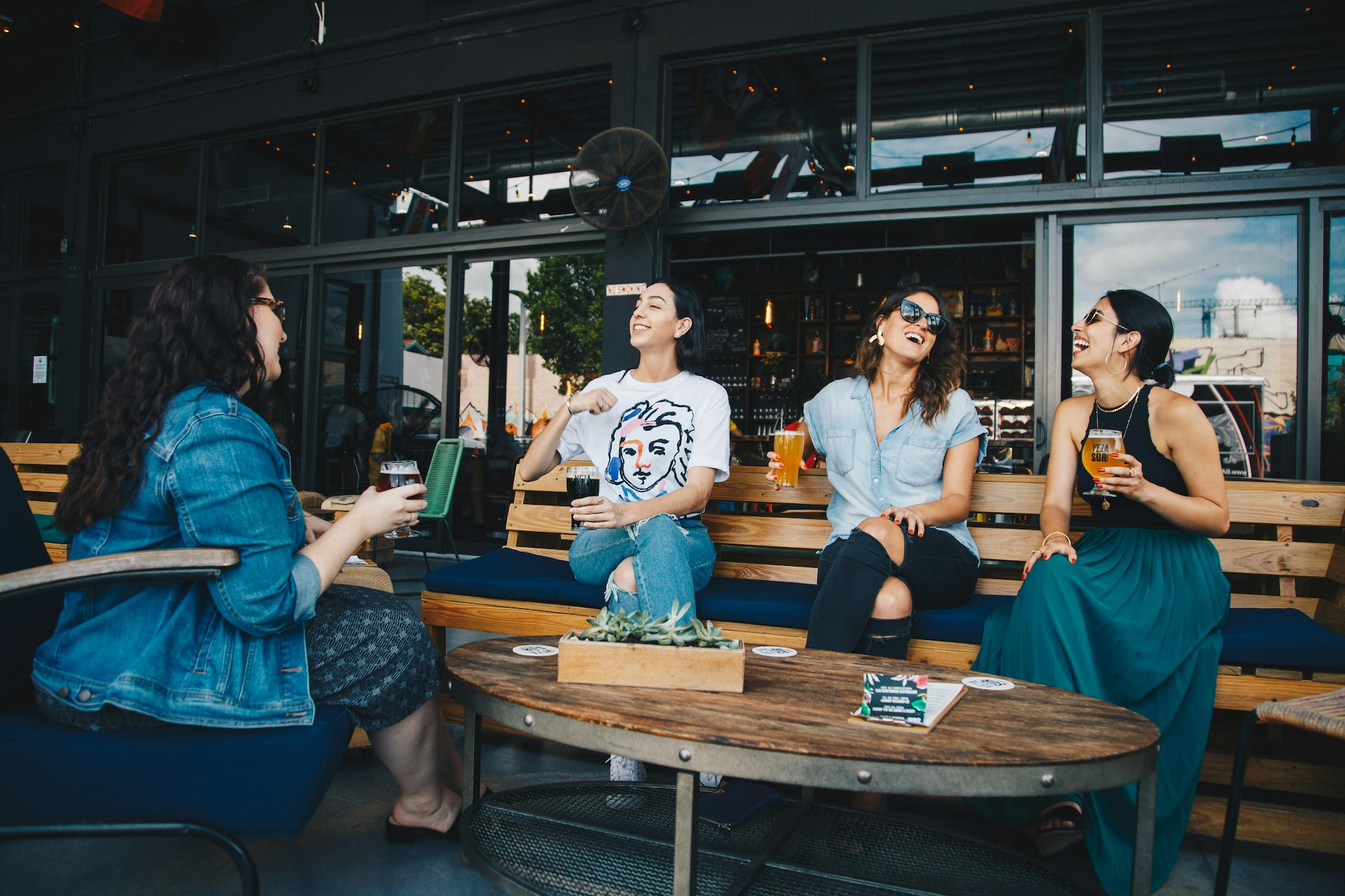 four women chatting while sitting outside a bar