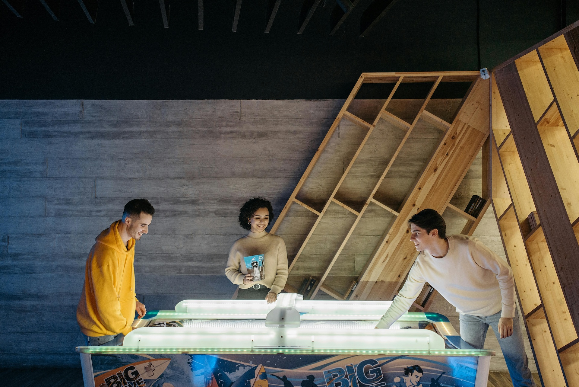 friends playing air hockey bar game