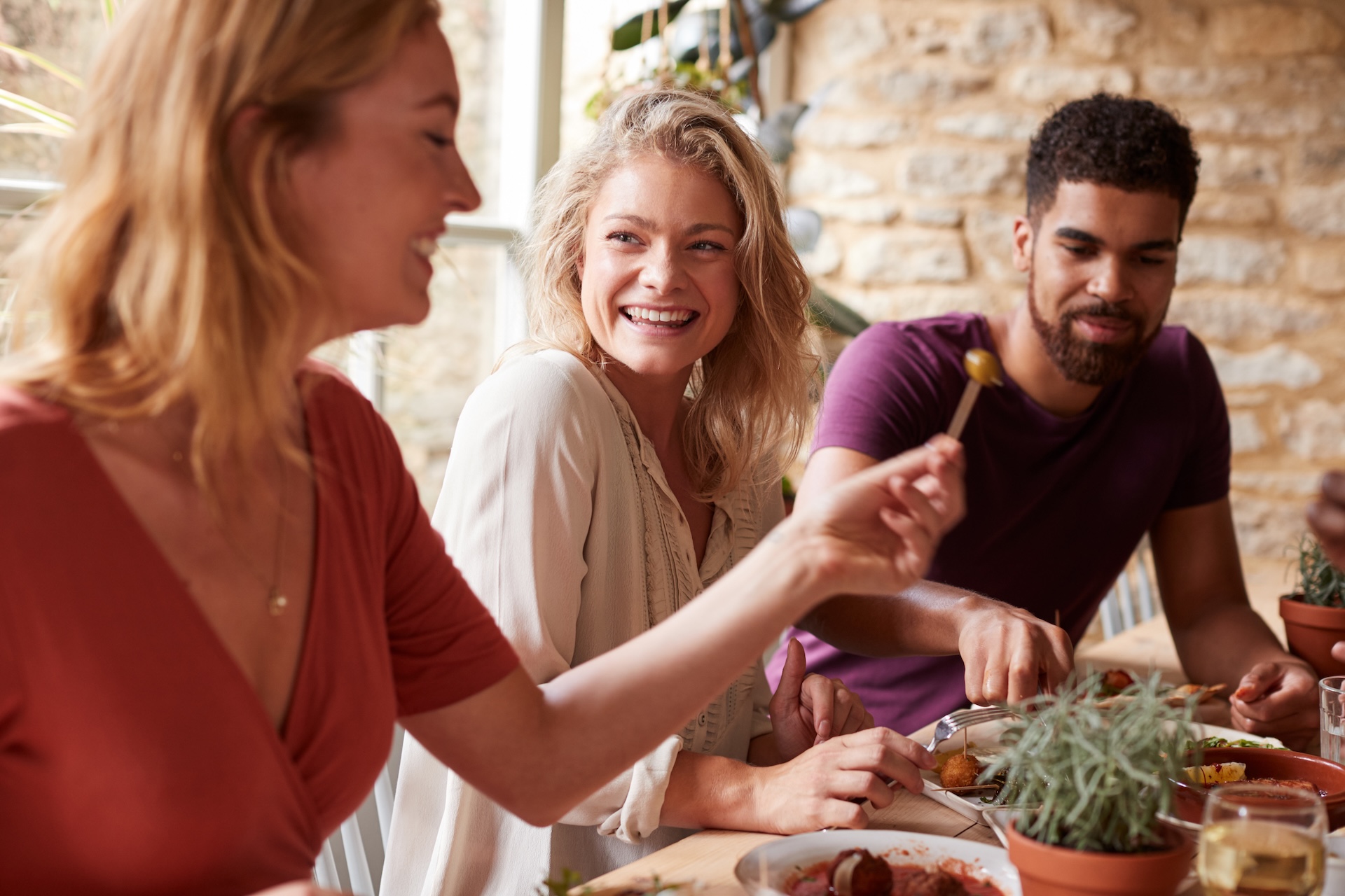 Three young friends having fun eating bar tapas at a restaurant
