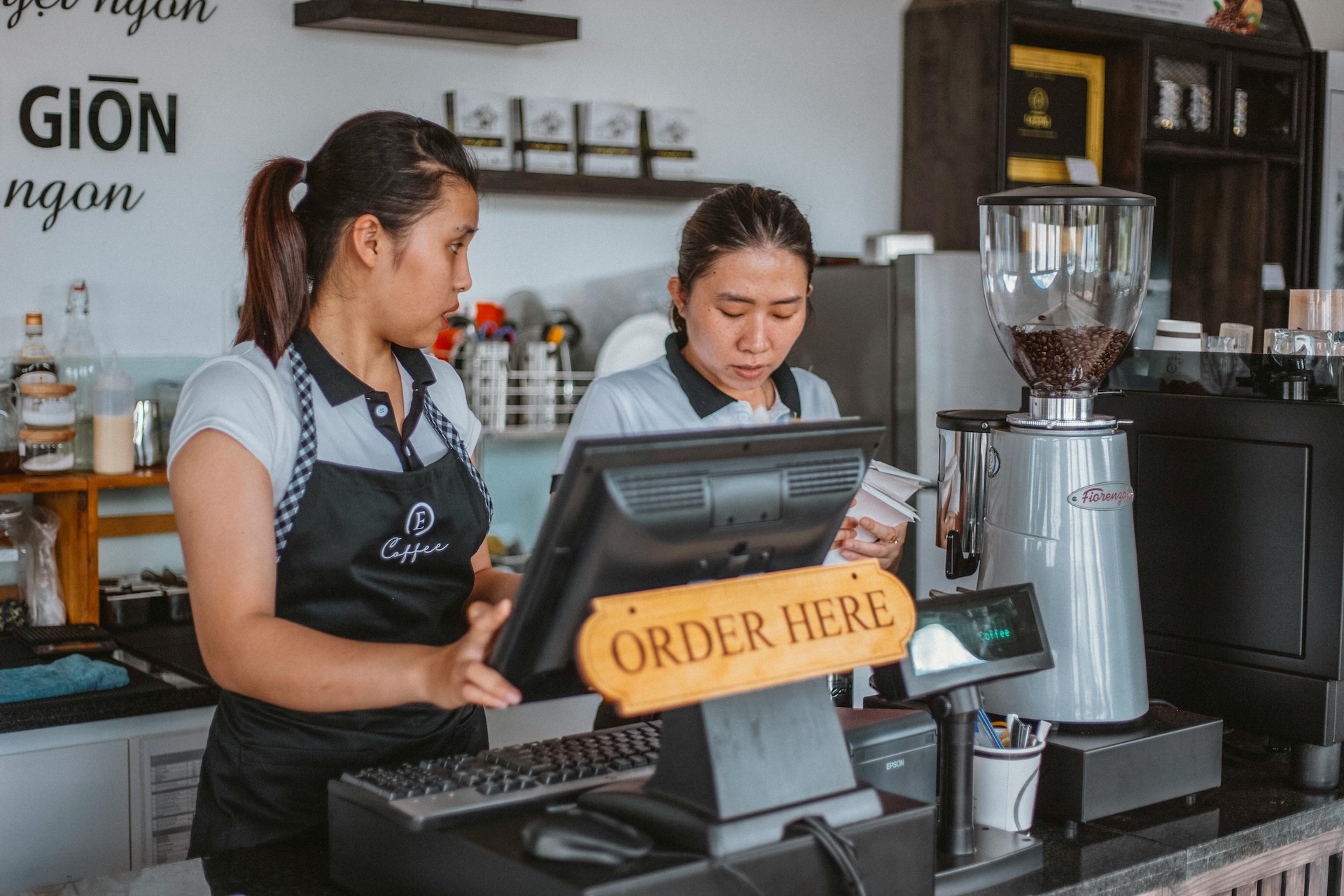 two waitresses with bills behind a cashier