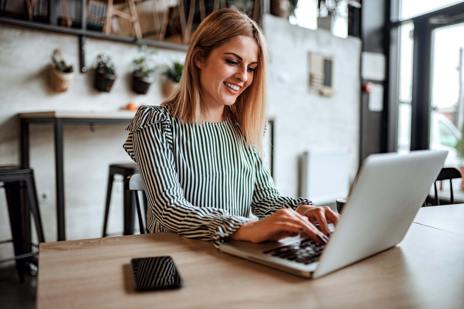 Smiling woman typing on laptop in restaurant